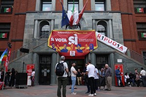 2025年6月4日星期三，在意大利米兰，人们站在支持就就业和意大利公民身份举行五项废除性全民公投的横幅旁。（图：路透社）