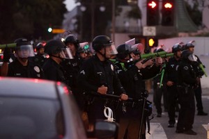 6月10日，在美国加利福尼亚州洛杉矶市中心，警察在宵禁生效后试图驱散街上的人群。（图：新华社）