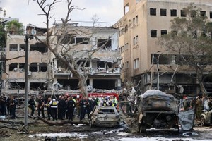 16日，在以色列特拉维夫，应急和救援人员在一处导弹袭击现场开展工作。（图：新华社）