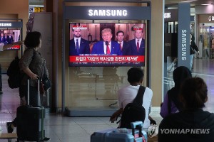 6月22日，在首尔站候车厅，旅客们正在收看美国总统特朗普发表电视讲话的新闻。（图：韩联社）