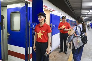 穿着红衫与金星制服的铁路员工正为统一列车乘客服务。（图：越通社）