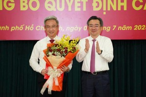 市委常务副书记阮青毅向市委副书记邓明通（左）颁授《决定》并赠送鲜花表示祝贺。（图：TV）