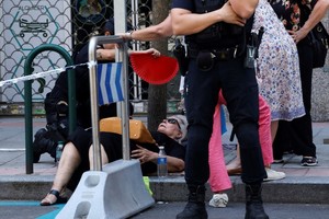 当地时间2025年7月5日，西班牙马德里，一名女子在街上因中暑晕倒，警察为她扇风降温。（图：互联网）