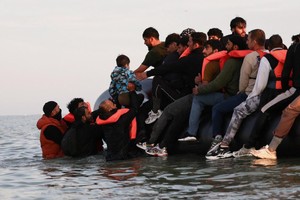 7月17日，一群移民在法国北部加莱附近一处海滩登上充气艇，希望穿越英吉利海峡到达英国。（图：路透社）