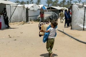 一名男孩在加沙流离失所者营地搬运物品。