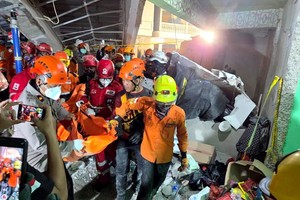 10月1日，救援人员在印度尼西亚东爪哇省诗都阿佐县建筑倒塌现场搬运遇难者遗体。（图：新华社）