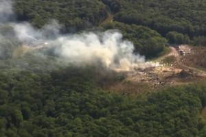 爆炸现场浓烟滚滚，周围散落着汽车残骸。（图：AP）