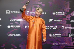 越南演员连炳发穿长衫登台，开心高举奖座留影。（图自中央通讯社）