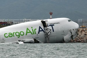 一架货机在香港国际机场降落时偏离跑道，部分机身沉入海中，救援人员在飞机周围进行救援。（图：路透社）