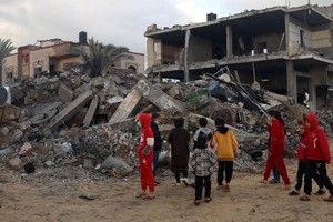 加沙地带南部的拉法市，孩子们走在被炸毁的房屋废墟间。