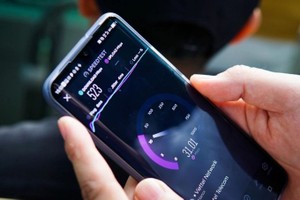 用户正在手机上打开Speedtest应用程式进行网络测速。