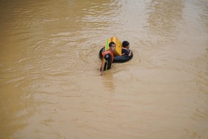 11月20日，民众带着自制浮具穿过西芽庄坊的淹水点。图：裴全
