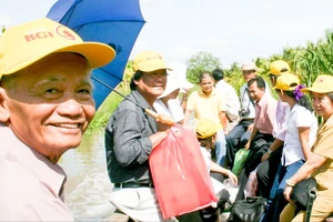 Anh Lê Minh Châu (bìa trái) đi xuồng vào thăm gia đình Anh hùng liệt sĩ Trần Thị Anh, năm 2010