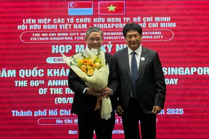 越新友好协会代表（右）向新加坡驻胡志明市总领事彭迪成赠送献花。图自《西贡解放报》 