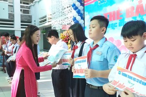 棋盘初中学校校长阮氏清泉在新学年开学典礼上向学生赠送医保卡。 