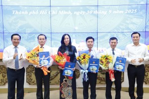 胡志明市人委会主席阮文得与胡志明市人委会副主席裴春强向武黄银（右三）及市规划与建筑厅各副厅长颁授决定并献花祝贺。