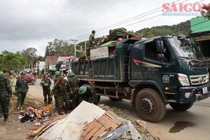 第七军区干部、战士帮助居民清理房屋和沿着林同省德兰乡27号国道的道路。 