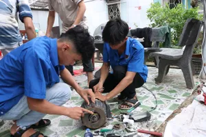 Các sinh viên sửa chữa thiết bị điện bị hư hỏng cho người dân sau mưa lũ