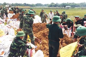 Military soldiers help residents fortify embankments in Quoc Oai district, Hanoi (Photo: SGGP)