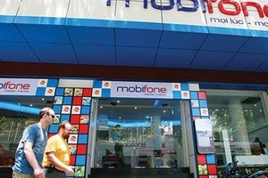 Two foreigners walk pass a customer centre of Mobifone, a State-owned enterprise (SOE) which was under equitisation process. Transparency in privatising SOEs must be enhanced to attract foreign strategic investment. (Photo: vneconomy.vn)