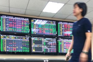 An investor passes by trading screens at Tan Viet Securities Company in Hanoi. (Photo: VNA)