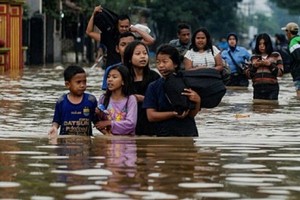 Residents walking along a flooded road as they evacuate Dayeuhkolot village in Bandung. (Photo: AFP)