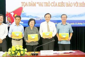 Mr. Hoang Chi Hung (L), chairman of the Press Photo Club under HCMC Journalists Association gives delegates at the seminar photobooks on sea and islands (Photo: SGGP)