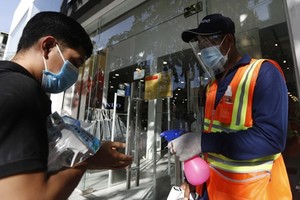 A shopper has his hands sprayed with sanitiser before entering a shop in Cambodia (Photo: khmertimeskh.com)
