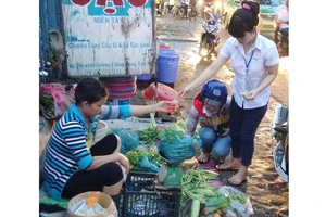 Công nhân tan ca chọn mua rau tại chợ tự phát trên đường Lê Văn Chí, quận Thủ Đức. Ảnh: HẢI THU