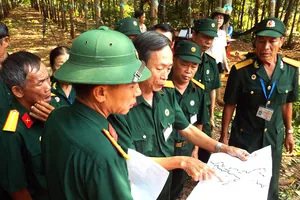 Thương binh Vũ Đình Luật (người chỉ tay vào bản đồ) trong lần đi tìm hài cốt đồng đội
