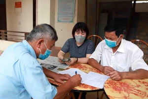 Chi trả tiền hỗ trợ cho người dân gặp khó khăn do COVID-19. Ảnh: TTXVN