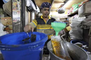 Người dân đong dầu ăn để bán tại một khu chợ ở Jakarta, Indonesia. Ảnh: AFP/TTXVN
