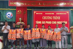 Phóng viên Báo SGGP và đại diện chính quyền địa phương trao áo phao cứu sinh tặng bà con ngư dân xã Cửa Việt, tỉnh Quảng Trị.