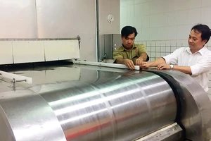 Anh Nguyễn Thanh Hiền (phải) cùng đồng nghiệp bên băng chuyền cấp đông IQF do anh cải tạo