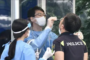 Nhân viên y tế lấy mẫu xét nghiệm COVID-19 cho một nhân viên an ninh tại Seoul, Hàn Quốc. Nguồn: TTXVN