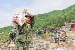 Các chiến sĩ thuộc Trung đoàn 971 (Bộ Chỉ huy Quân sự TP Đà Nẵng) vác từng bao tải đất đá ra ngoài để tìm mộ bị vùi lấp do sạt lở. Ảnh: XUÂN QUỲNH