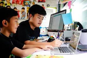 Em Nguyễn Huỳnh Thông, lớp 3 trường Võ Thị Sáu đang làm quen với cách học trực tuyến với sự hướng dẫn của người anh Nguyễn Huỳnh Bách, lớp 7 trường Đinh Thiện Lý. Ảnh: THANH TÙNG