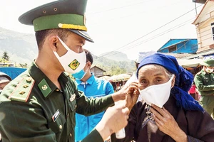  Các chiến sĩ Đồn Biên phòng Y Tý phát và hướng dẫn đồng bào các dân tộc đeo khẩu trang, phòng dịch Covid-19. Ảnh: ĐBP