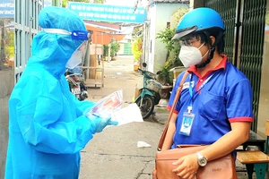 Anh Châu Tiến Lộc (phải), cán bộ Thành đoàn TPHCM, cùng nhân viên y tế nắm tình hình F0 điều trị tại nhà