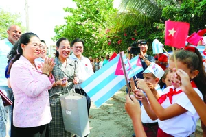 Các em học sinh làng Bến Tre đón đoàn đại biểu TPHCM đến thăm. Ảnh: NGÔ BÌNH 