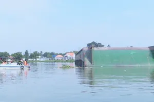 Lực lượng tìm kiếm xung quanh chiếc sà lan bị lật úp đề tìm người mất tích dưới sông. Ảnh: TTXVN