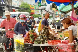 Khách hàng chọn mua bánh ú, trái cây sát chợ Hòa Hưng, quận 10, TPHCM, sáng 18-6. Ảnh: THI HỒNG