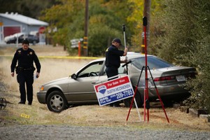 Law enforcement officers examine a vehicle that was involved in a shooting Tuesday, in Rancho Tehama, California. Four people were killed and nearly a dozen were wounded, including several children, when a gunman went on a rampage at multiple locations, i