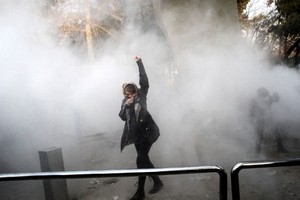 A woman raises her fist amid tear gas at the University of Tehran during a protest on December 30, 2017. – AFP/VNA Photo