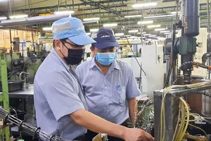 Anh Lê Chí Chung (trái, Công ty Juki) cùng đồng nghiêp tìm hiểu hoạt động của máy để đưa ra sáng kiến cải tiến. Ảnh: THÁI PHƯƠNG