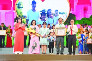 Phó Bí thư Thành ủy TPHCM Nguyễn Văn Hiếu và Phó Chủ tịch UBND TPHCM Phan Thị Thắng chúc mừng các gia đình được tuyên dương. Ảnh: PHƯƠNG NGHI