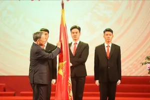 Tổng Bí thư Tô Lâm gắn Huân chương Lao động hạng Nhất lên lá cờ truyền thống. Ảnh: VIẾT CHUNG