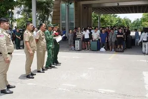 Lực lượng chức năng Việt Nam và Campuchia làm thủ tục bàn giao, tiếp nhận công dân được trao trả. Ảnh: TTXVN