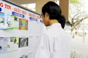 Học sinh tìm hiểu cách phòng chống tác hại thuốc lá tại bảng tuyên truyền Ảnh: NGÔ ĐỒNG