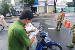 Công an hướng dẫn người dân khai báo tại chốt trạm kiểm soát ở TPHCM sáng ngày 29-8. Ảnh: CHÍ THẠCH 